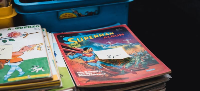 comic books and children's books priced and stacked in a garage sale