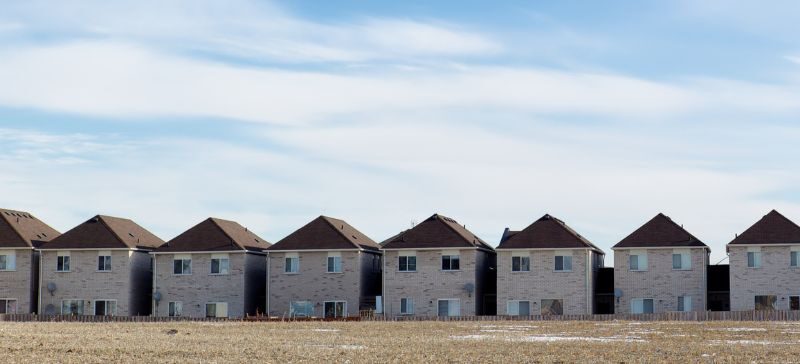 multiple row houses that conform to look exactly the same with a blue sky and clouds behind