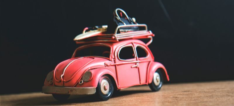 vintage Volkswagen with roof-top rack with luggage and a surf board on top