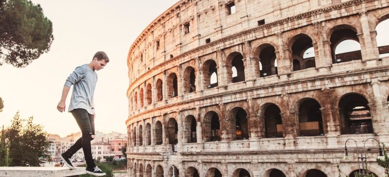 A man walking on a wall in front of the Roman Coliseum