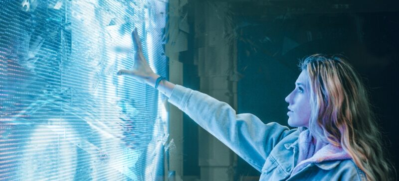 Woman reaching toward a large touch screen.