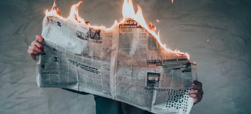 Person holding burning newspaper.