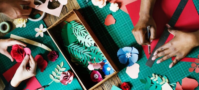 Three people cutting craft paper into flowers