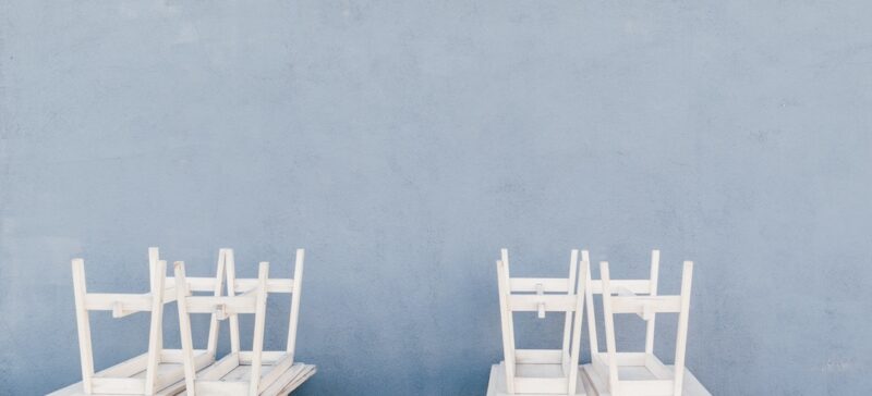 Two white tables with chairs stacked on top of them