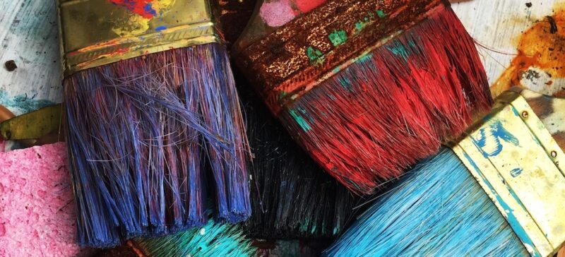 A pile of colorful, dirty paintbrushes