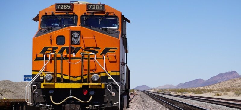 A large orange train gaining momentum on the tracks