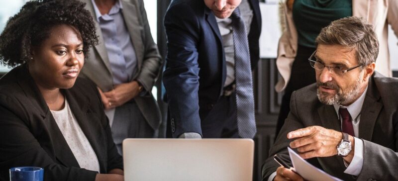 Business leaders crowding around a computer