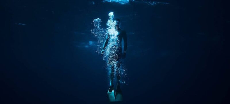 Man swimming alone in a dark body of water