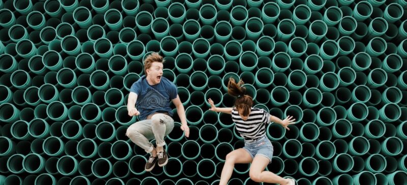 A man and woman jumping in front of a green background