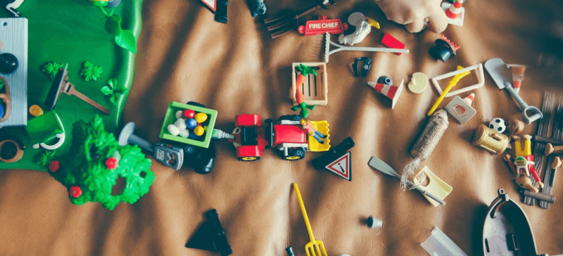 A child playing with broken toys on a brown sheet