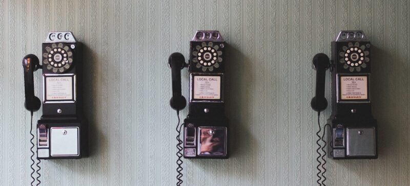 three black payphones on a white wall
